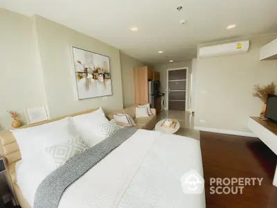 Elegant bedroom with a plush king-size bed, modern art, and sleek wooden flooring, complemented by a cozy sitting area and ample natural light.