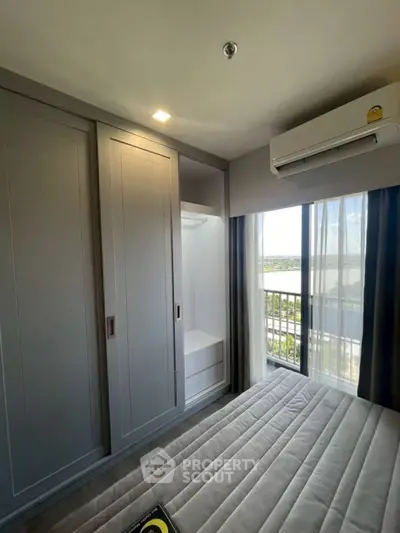 Modern bedroom with built-in wardrobe and air conditioning, featuring a large window with a scenic view.