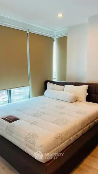 Modern bedroom with large windows and stylish bed in a high-rise apartment.