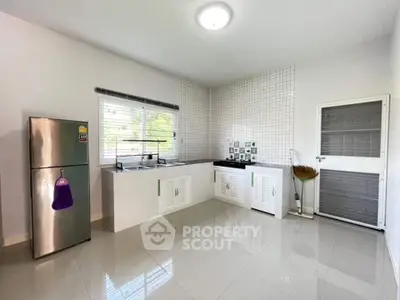 Modern kitchen with sleek design, stainless steel fridge, and ample natural light.