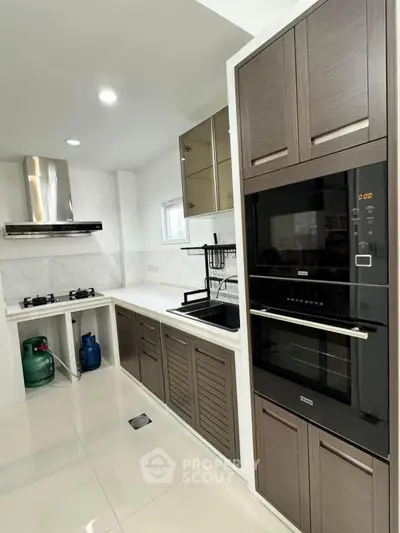 Modern kitchen with sleek cabinetry, gas stove, and built-in oven in a contemporary home.