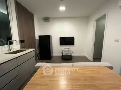 Modern studio apartment with sleek kitchenette, full-sized fridge, and cozy living space, perfect for urban living.