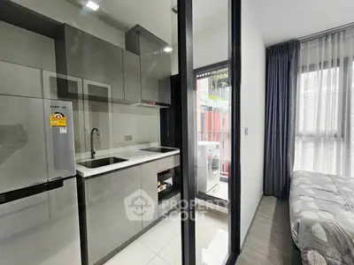 Modern compact kitchen with sleek cabinetry and adjacent cozy bedroom