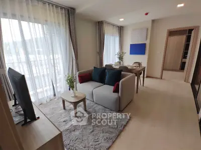 Modern living room with stylish decor and natural light, featuring a cozy sofa and dining area.