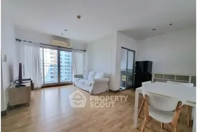 Spacious living room with modern furniture and large windows in a high-rise apartment.