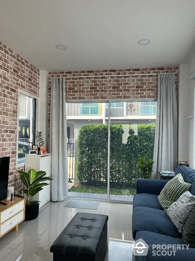 Modern living room with brick accent wall and large window overlooking garden