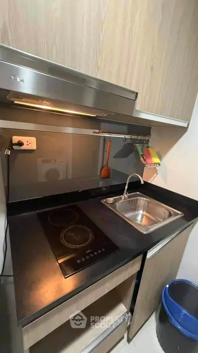 Modern compact kitchen with electric stove and sleek cabinetry in urban apartment.