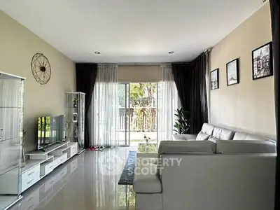 Spacious living room with modern decor and large windows offering natural light and garden view.
