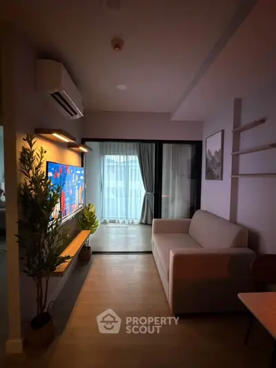 Modern living room with cozy sofa and large TV, featuring elegant decor and natural light from large windows.