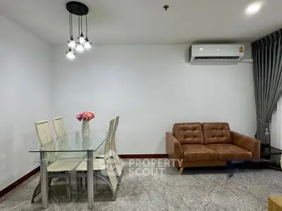 Modern living room with glass dining table, leather sofa, and elegant lighting.