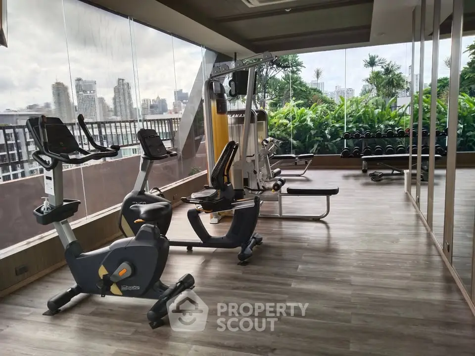 Modern gym with city view and state-of-the-art equipment in luxury apartment building.