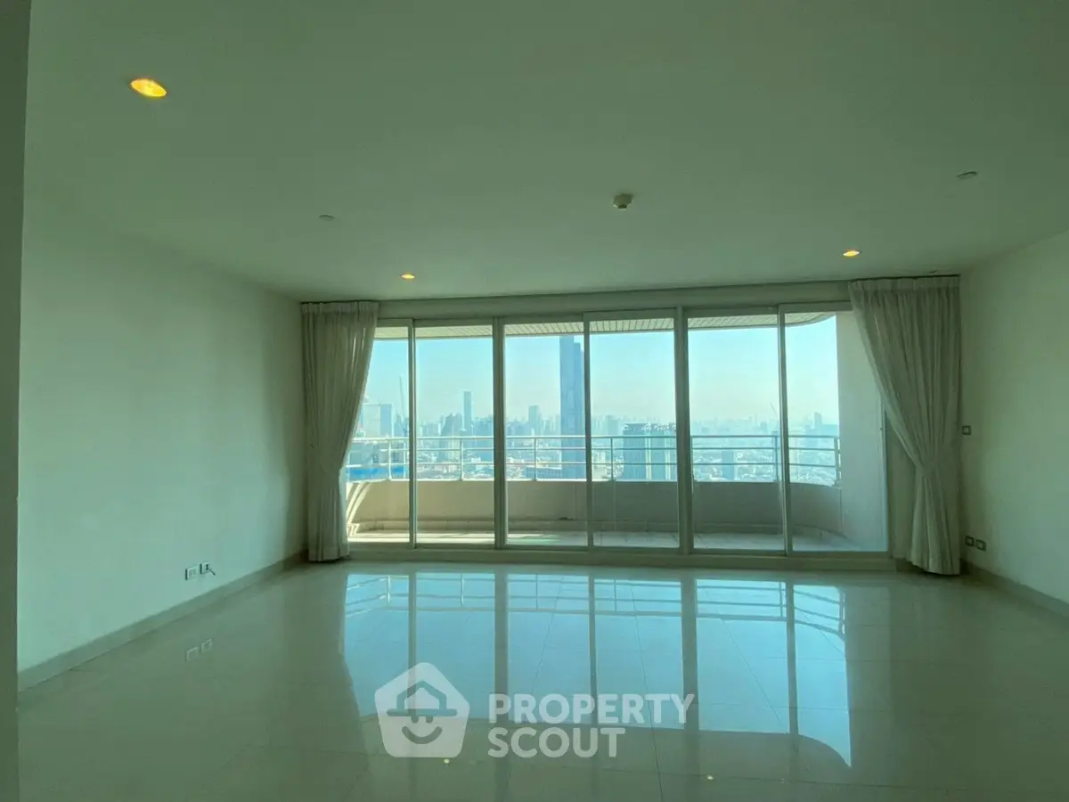 Spacious living room with floor-to-ceiling windows offering stunning city skyline views.