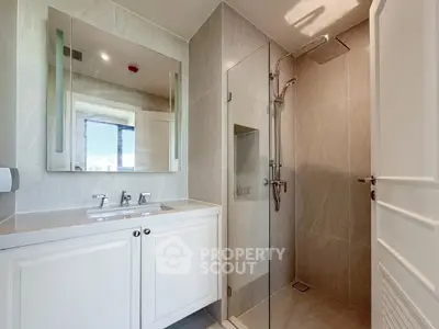 Modern bathroom with glass shower and elegant vanity in luxury apartment.