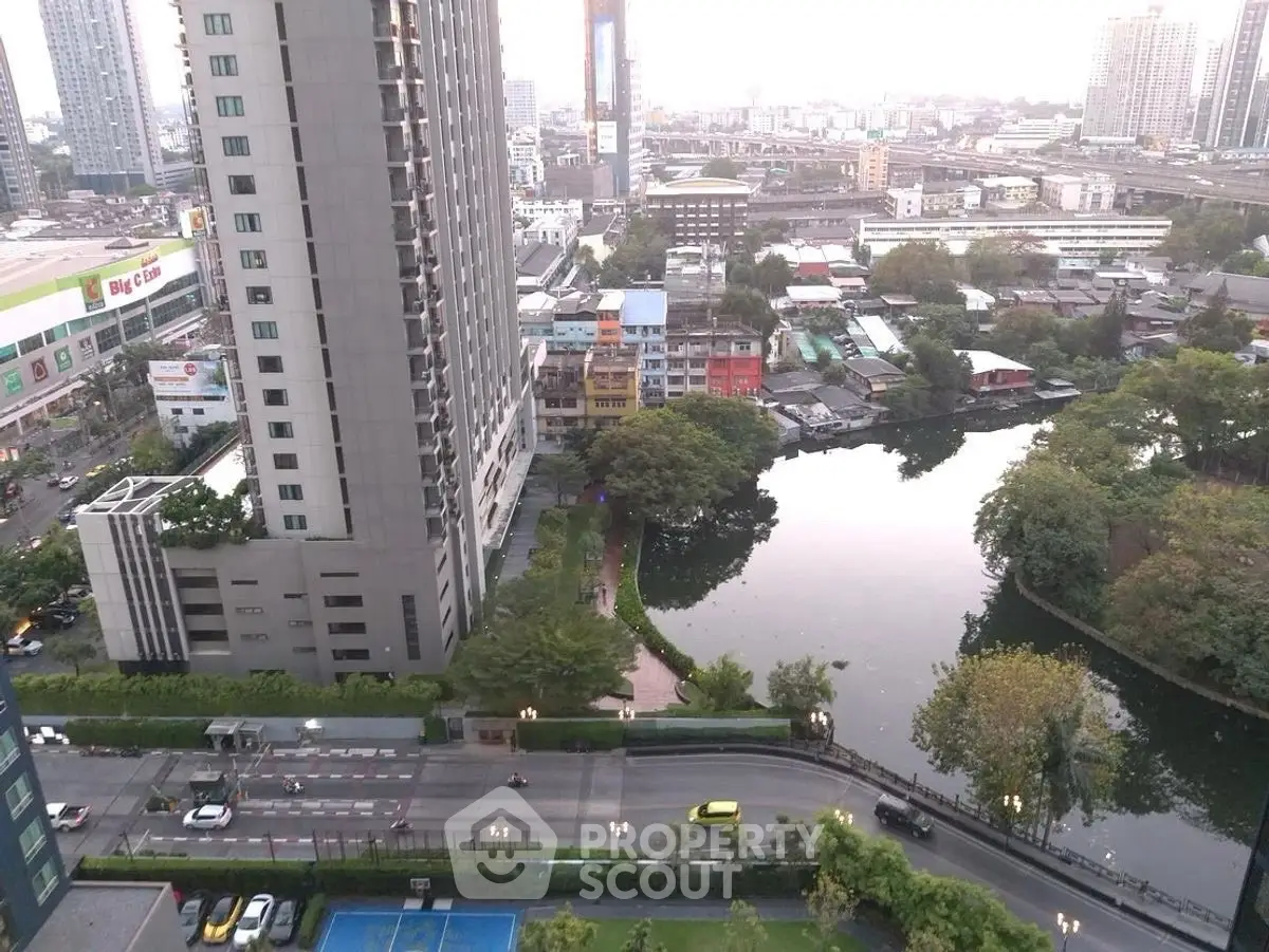Stunning cityscape view from high-rise building overlooking serene pond and urban skyline.