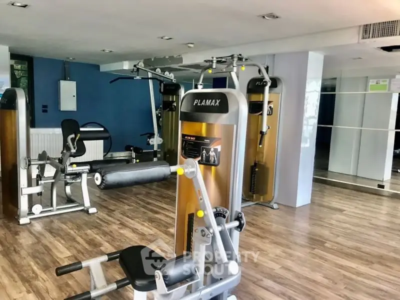 Modern gym with state-of-the-art fitness equipment and wooden flooring in a residential building.