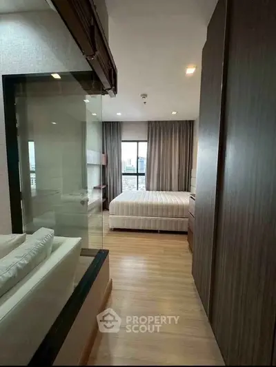 Modern bedroom with glass partition and wooden flooring in a stylish apartment.
