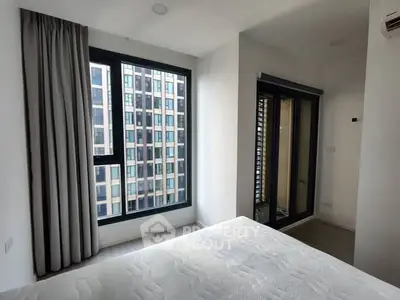 Modern bedroom with large window and city view in high-rise apartment.
