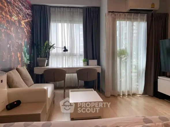 Modern living room with stylish decor and natural light, featuring a cozy seating area and work desk.