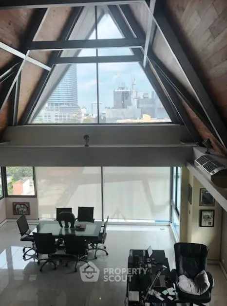 Stunning loft office with high ceilings and city view, featuring modern furniture and ample natural light.