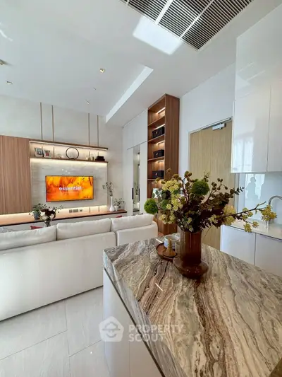 Modern living room with stylish decor and open layout, featuring a large TV and elegant furnishings.