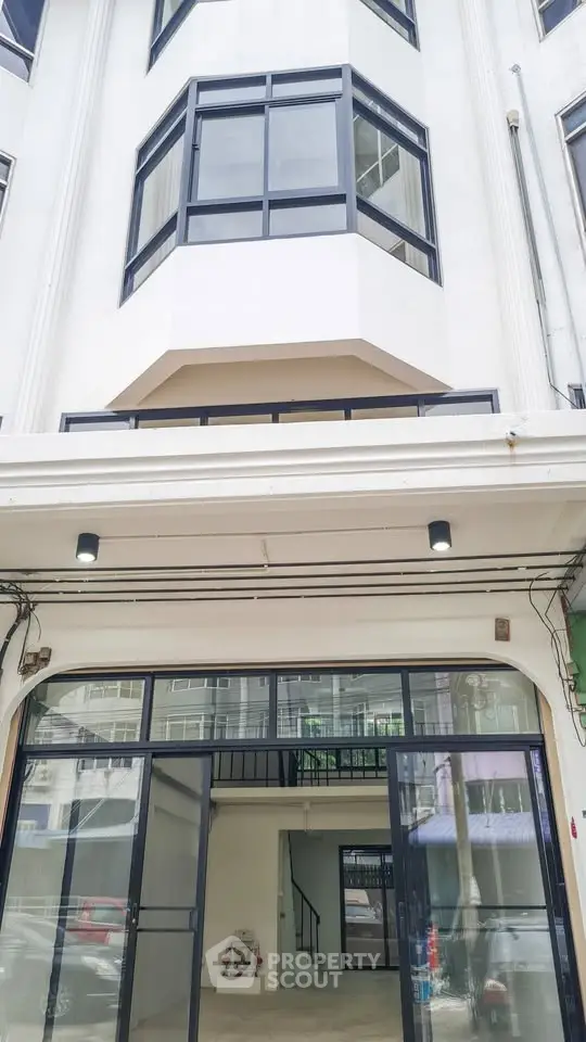 Modern building exterior with large windows and glass entrance, showcasing sleek architectural design.