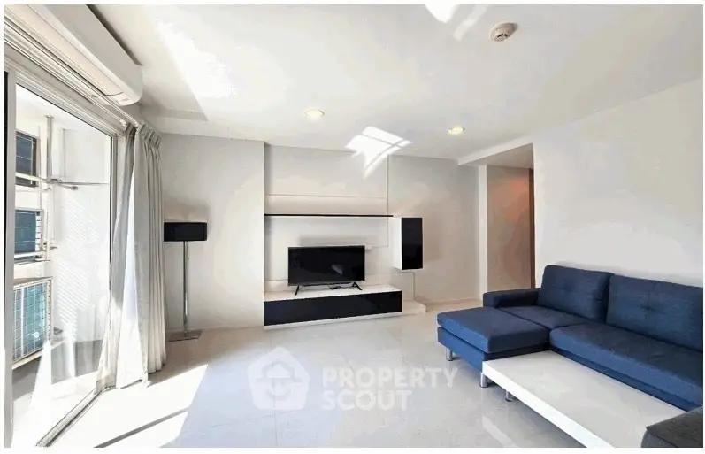 Bright modern living room with sleek blue sofa and large window view.