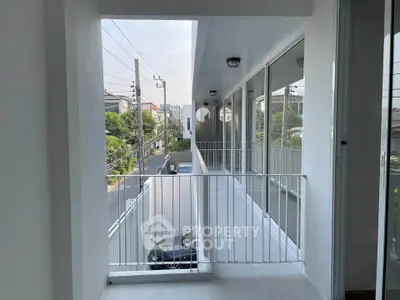 Modern apartment balcony with street view and sleek glass railing design.