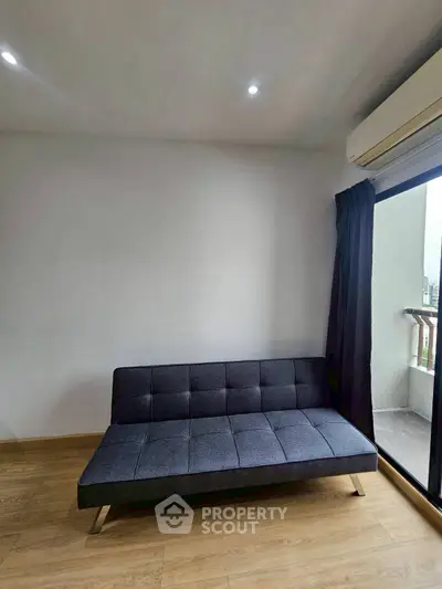 Modern minimalist living room with sleek gray sofa and balcony view.