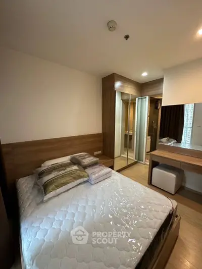 Modern bedroom with wooden accents and mirrored wardrobe in stylish apartment.