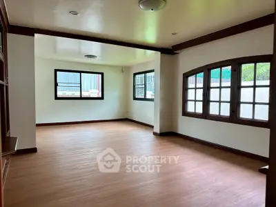Spacious living room with wooden flooring and large windows for natural light.