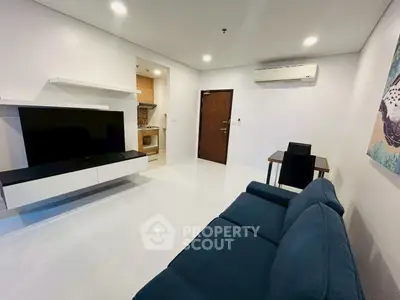 Modern living room with sleek furniture and open kitchen layout in a stylish apartment.