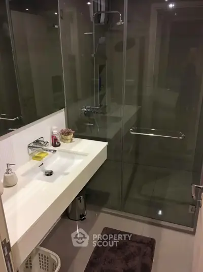 Modern bathroom with glass shower and sleek white sink in a contemporary home.