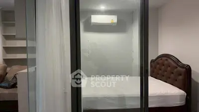 Modern bedroom with glass partition and air conditioning, featuring a stylish bed and cozy sofa.
