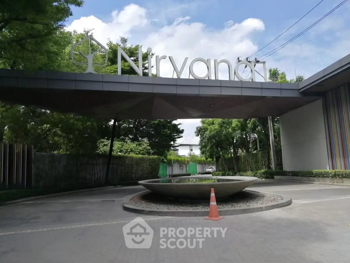 Modern entrance of Nirvana residential complex with sleek design and lush greenery.