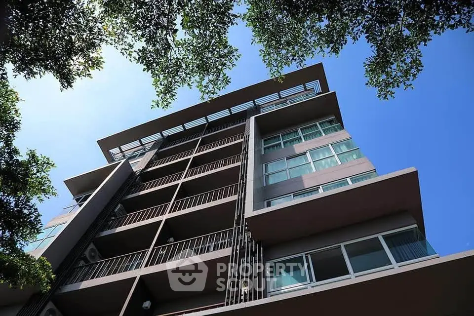 Modern apartment building with sleek design and large windows under a clear blue sky.