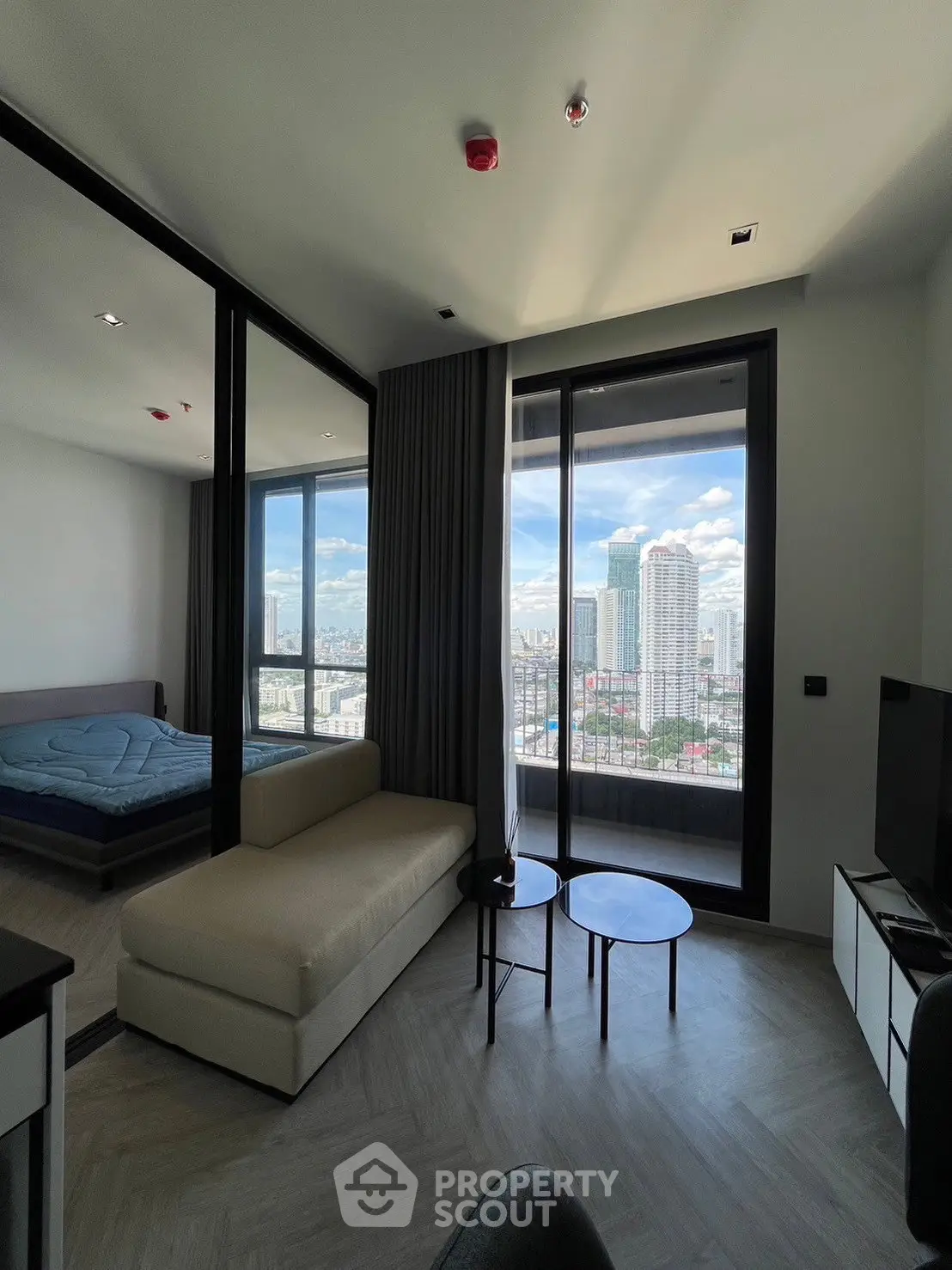 Modern living room with city view, featuring sleek furniture and large windows for natural light.