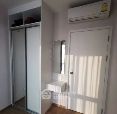 Modern bedroom with mirrored closet and air conditioning unit, featuring sleek design and natural light.