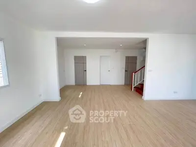 Spacious open-plan living area with modern wooden flooring and ample natural light