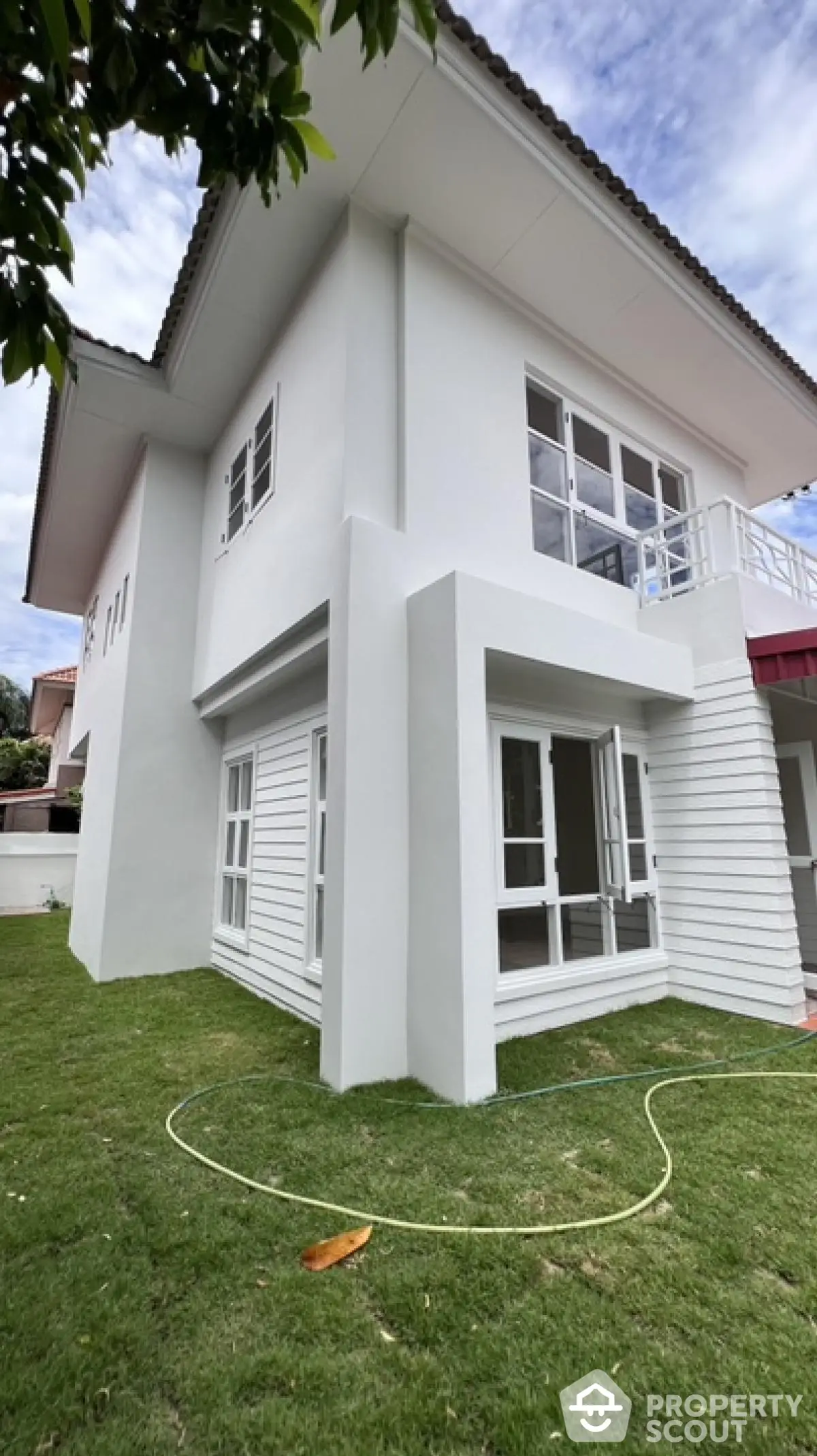 Modern two-story white house with large windows and lush green lawn