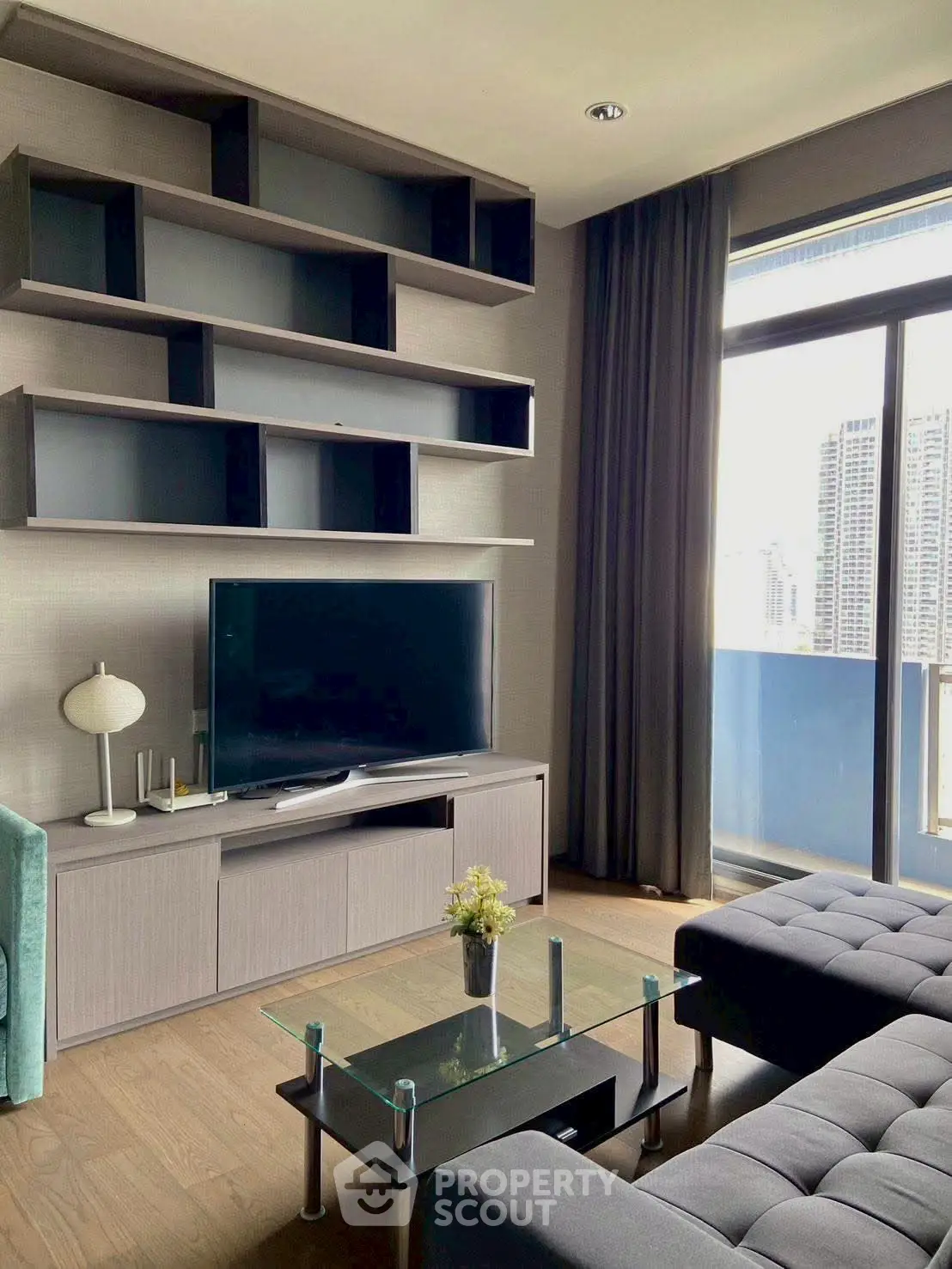 Modern living room with sleek furniture and city view from large window.