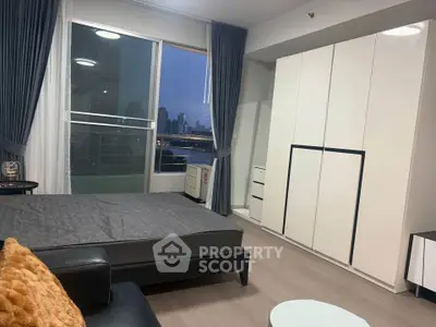 Modern bedroom with city view, sleek wardrobe, and cozy furnishings in a high-rise apartment.