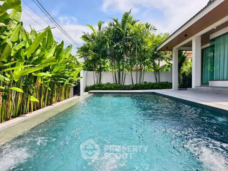 Luxurious private pool surrounded by lush greenery in a modern villa setting.