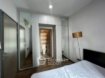 Modern bedroom with mirrored closet doors and ensuite bathroom in stylish apartment.