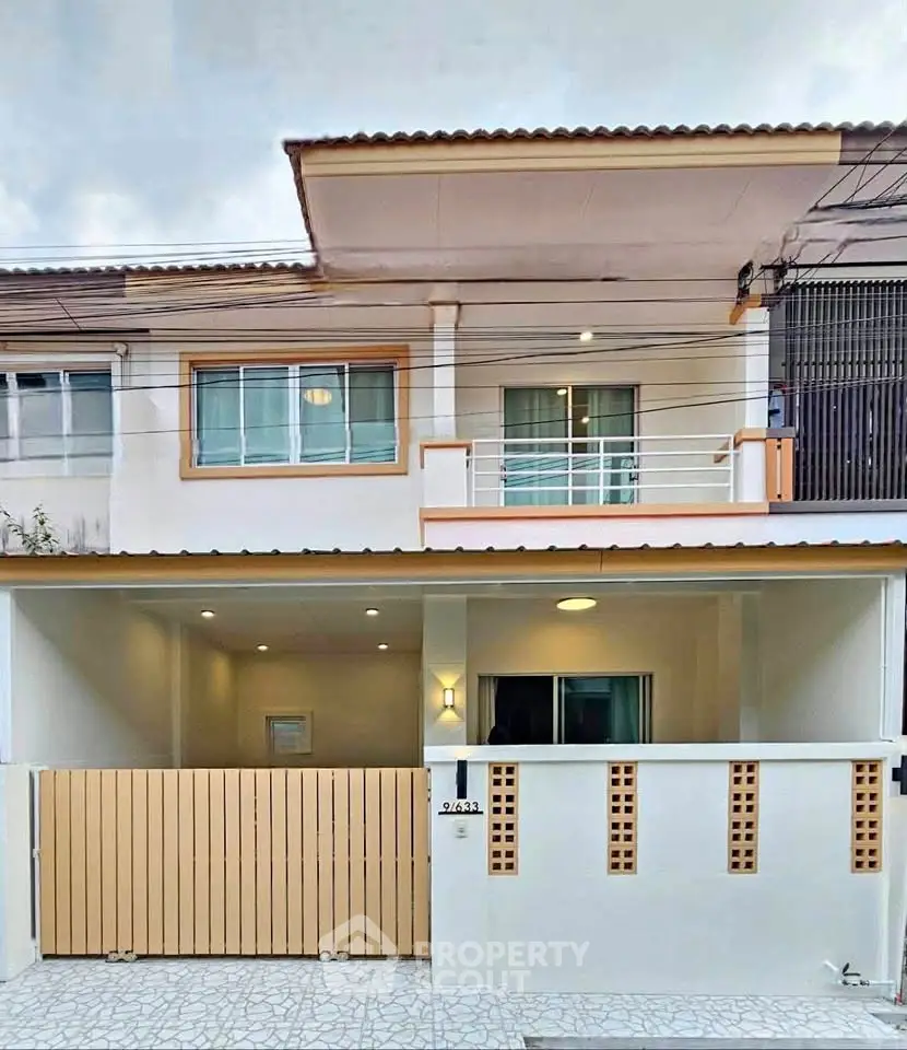 Modern two-story townhouse with balcony and gated entrance, ideal for family living.