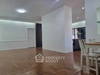 Spacious open-plan living area with wooden flooring and modern dining setup.
