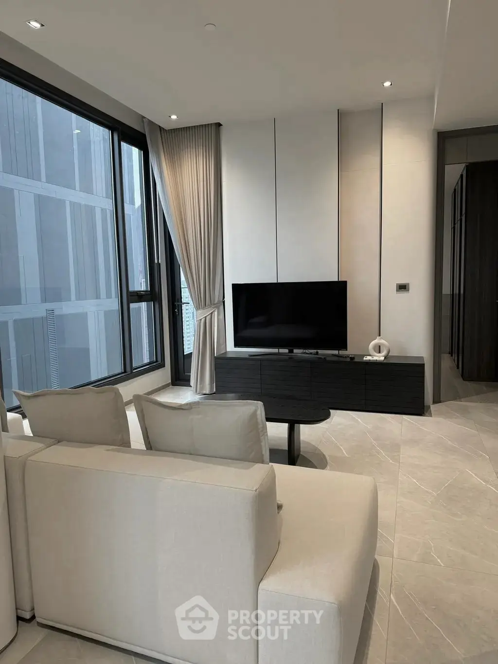 Modern living room with sleek design and large windows offering city views.