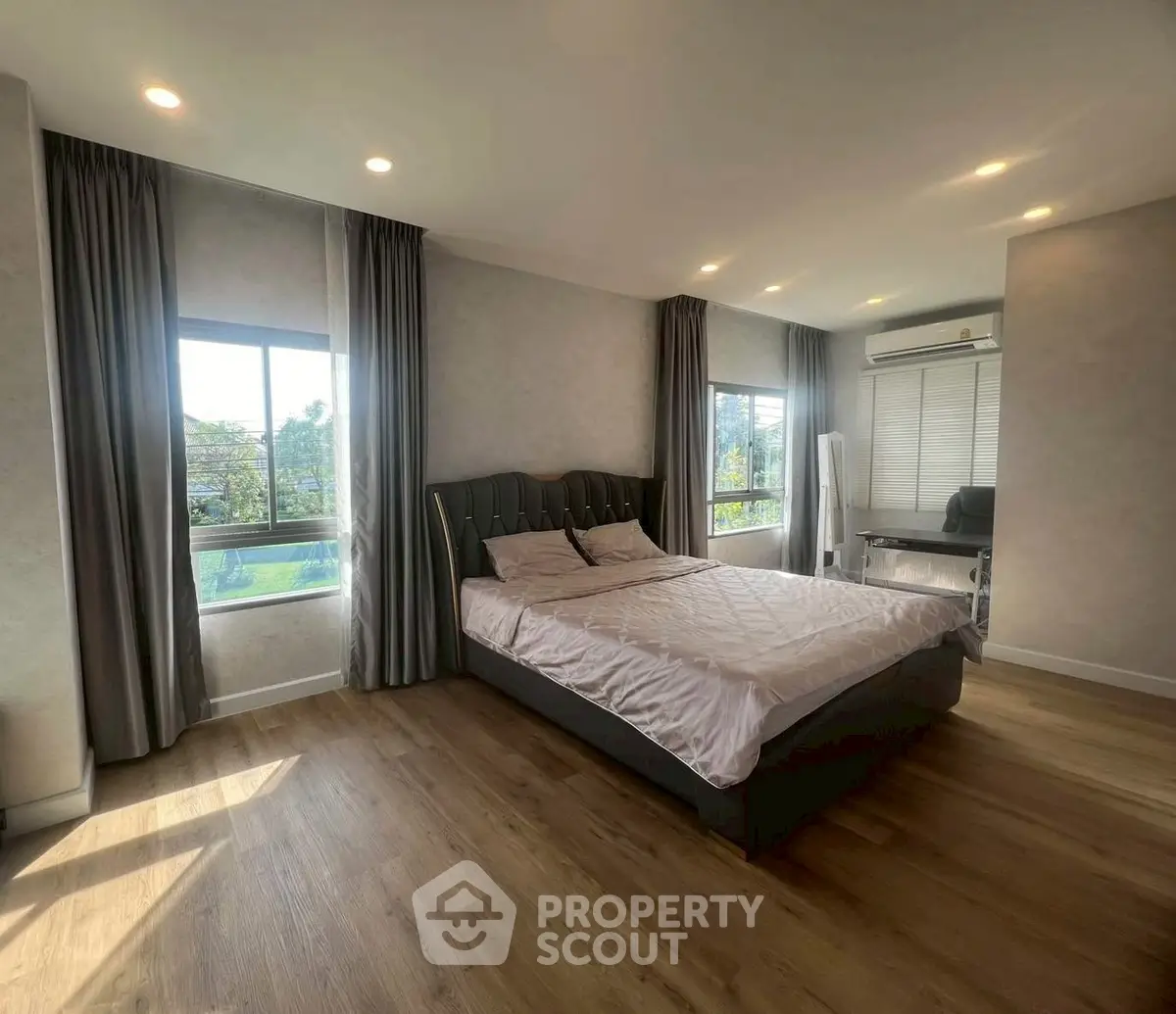 Spacious bedroom with large windows and elegant decor, featuring a comfortable bed and stylish flooring.