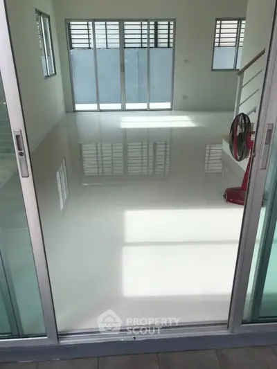 Spacious modern living room with large windows and sleek white flooring.