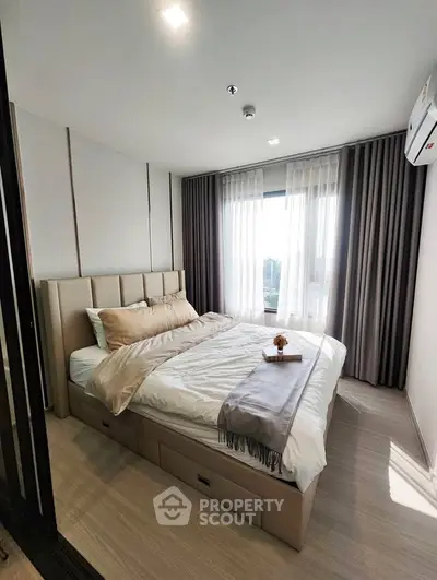 Modern bedroom with stylish decor and large window offering natural light