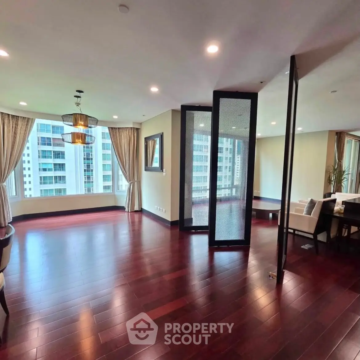 Spacious living room with hardwood floors and large windows offering city views.